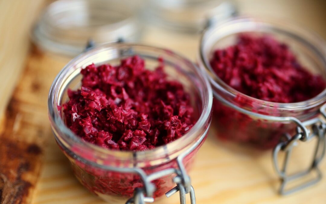 Zwei Gläser mit rotem Sauerkraut auf einem Holzbrett, Nahaufnahme.