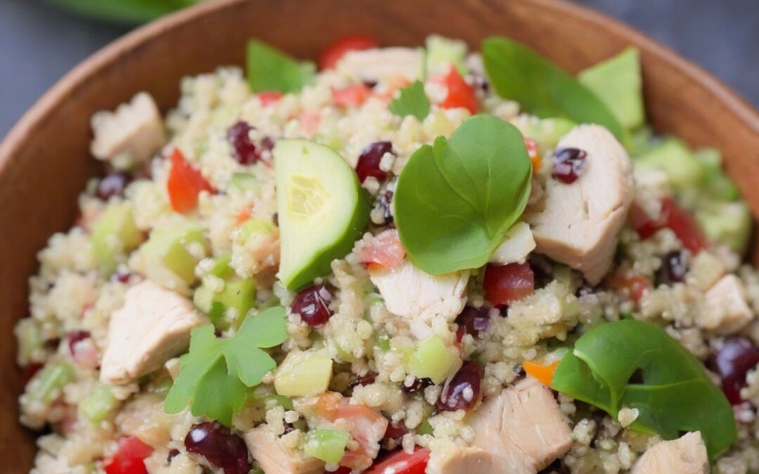 Bunter Couscous-Salat mit Hähnchen, Gurken, Paprika und frischen Kräutern in einer Holzschale.