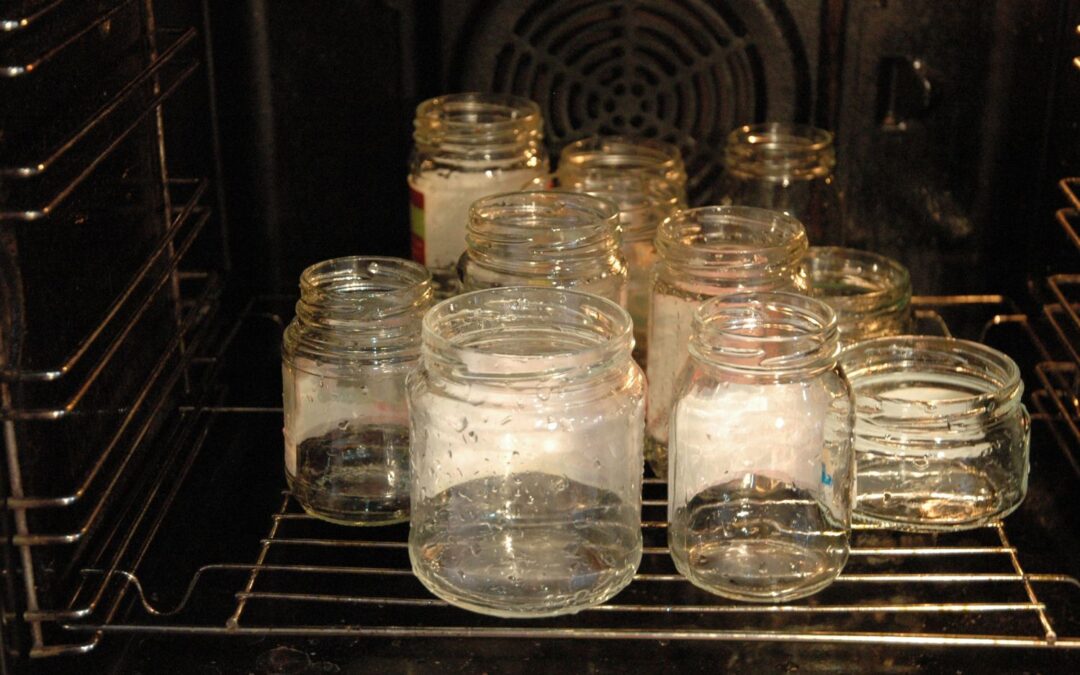 Glassgläser werden im Backofen sterilisiert. Sie stehen auf dem Rost und zeigen Kondenswasser.
