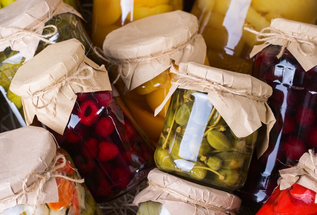 Fermentierte Lebensmittel in Gläsern auf einem Holztisch – gesund und selbstgemacht Mehrere Einmachgläser mit bunt fermentiertem Gemüse wie Karotten, Rotkohl und Gurken stehen nebeneinander auf einem Tisch vor neutralem Hintergrund.