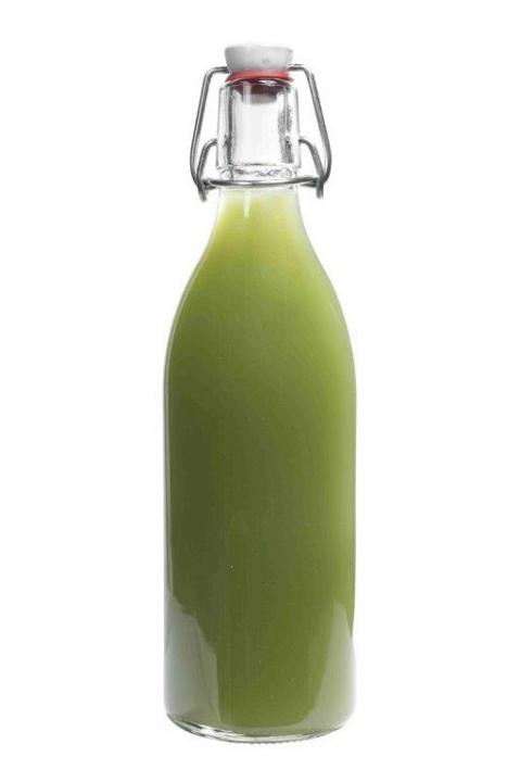 Sechs leere Glasflaschen mit Bügelverschluss in verschiedenen Farben auf weißem Hintergrund Sechs elegante grüne Glasflaschen in einer Reihe mit gestapelten Dosen im Hintergrund auf einem weißen Tisch, ideal für stilvolle Getränkepräsentationen und moderne Verpackungslösungen.